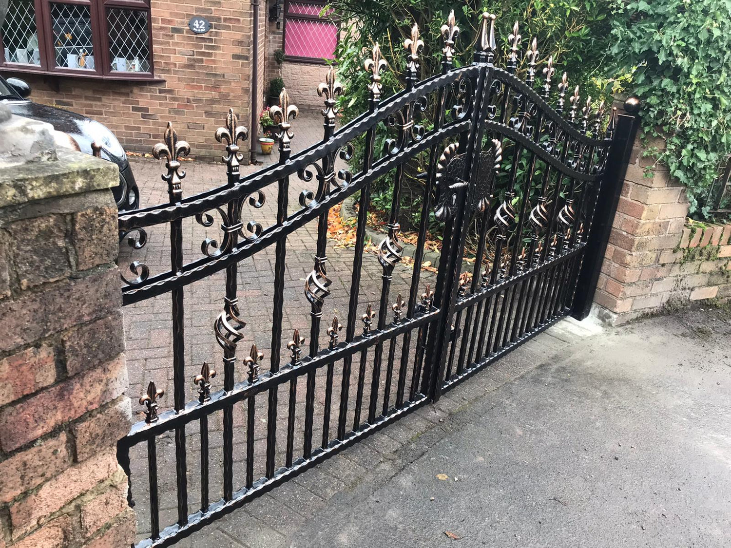 Wrought iron gate with black powder coating and antique copper highlights.